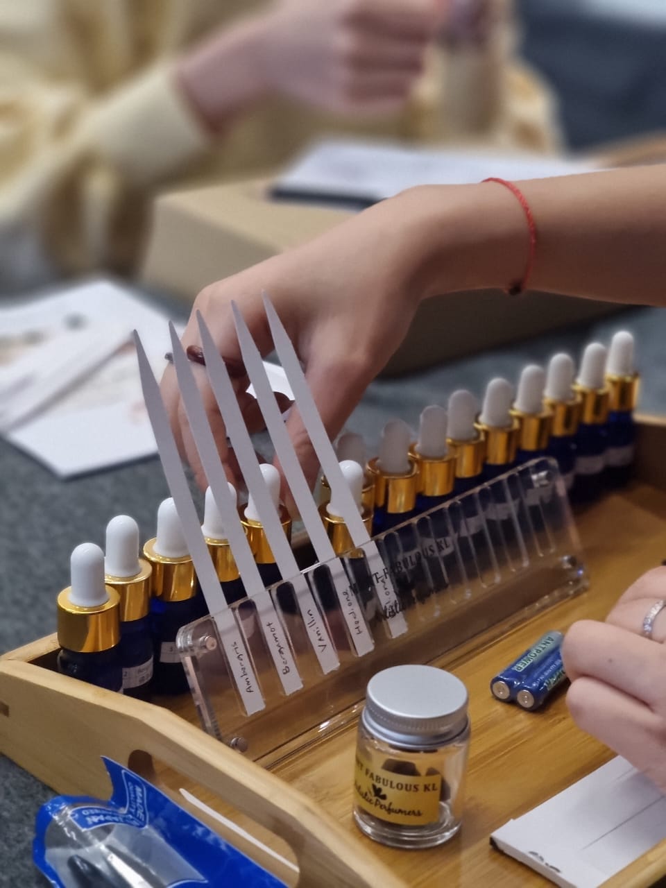 Hands exploring fragrance bottles during a perfumery workshop